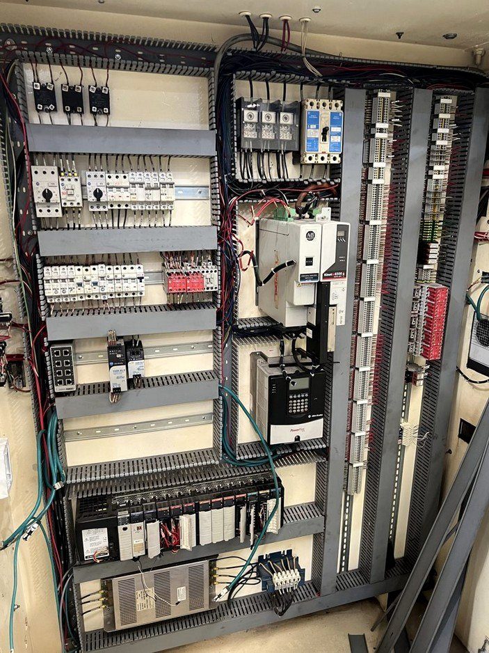 Tablero de control con variadores, PLC y contactores durante el desmantelamiento